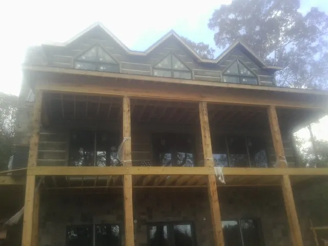 Dormers and porch framing on a large log home under construction — Roof Coating work by our crew in Ogdensburg