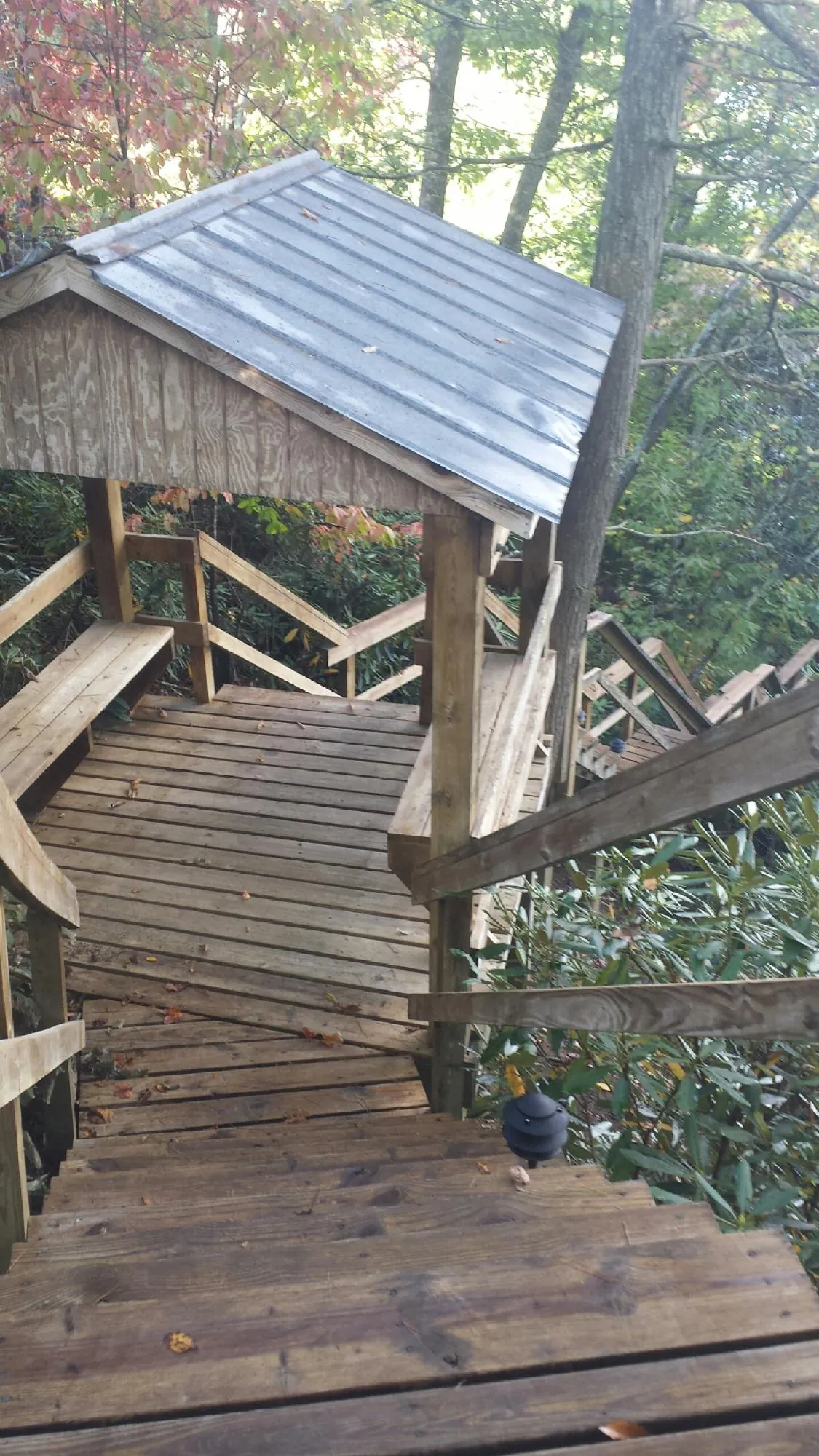 Metal roofed shelter over wooden steps on a wooded walkway — Skylight Repair & Installation work by our crew in Ogdensburg