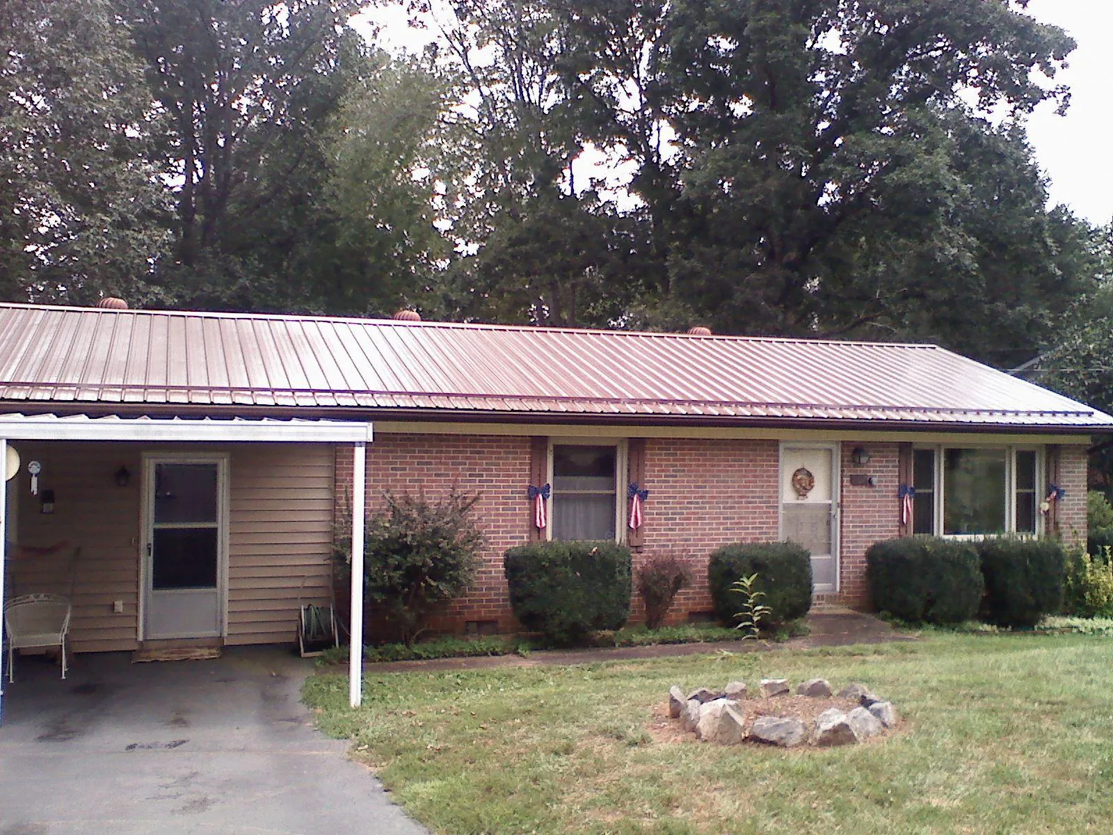 Bronze metal roof and carport on a brick ranch home — Roof Repair work by our crew in Ogdensburg
